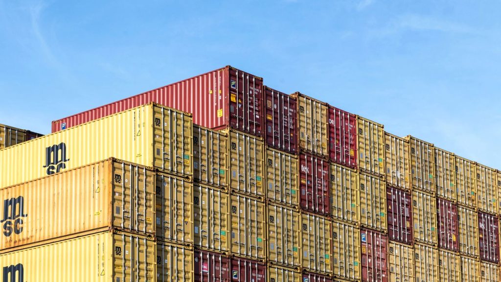Colorful stacked cargo containers in Hamburg port under a clear blue sky.