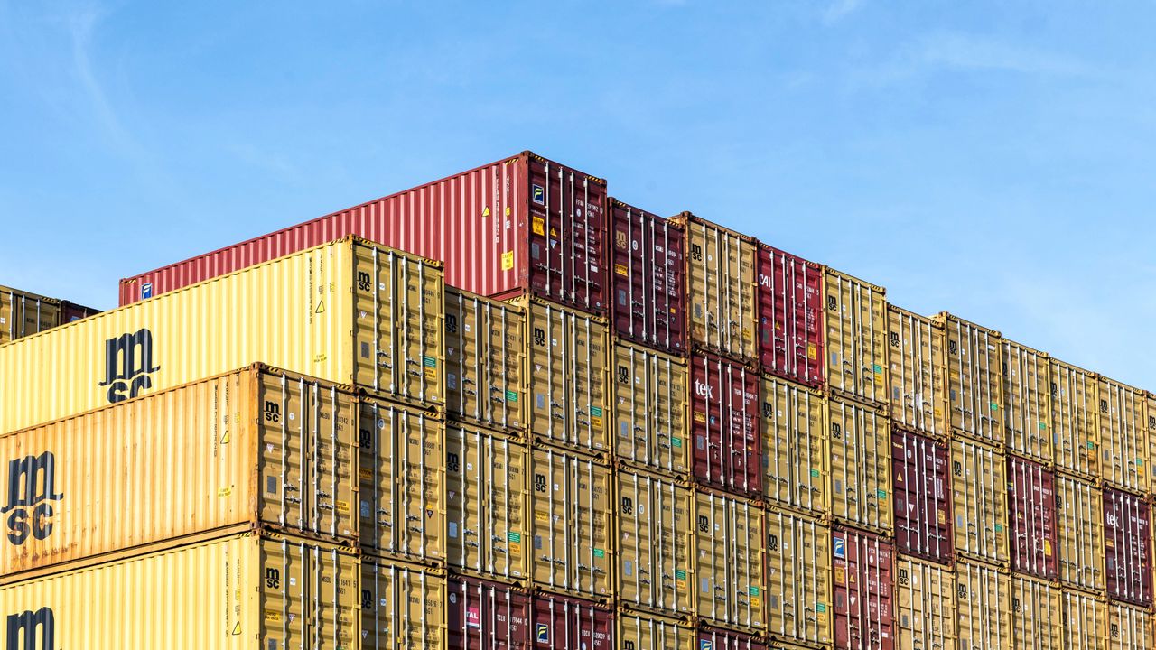 Colorful stacked cargo containers in Hamburg port under a clear blue sky.